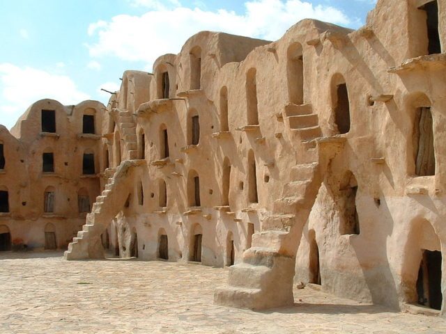 Many of the ghorfas are accessible by the steep steps that lead up from the courtyard floor. Author: Asram CC BY SA3.0