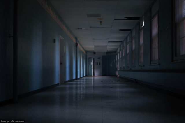 A dark hallway only lit by covered windows