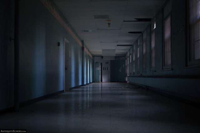 A dark hallway only lit by covered windows