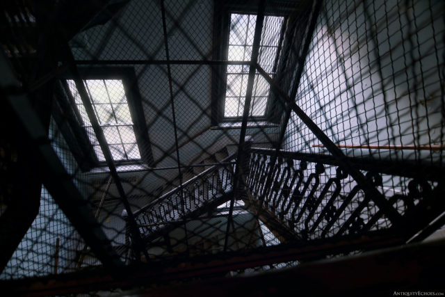 A downward view of a staircase through a gated window