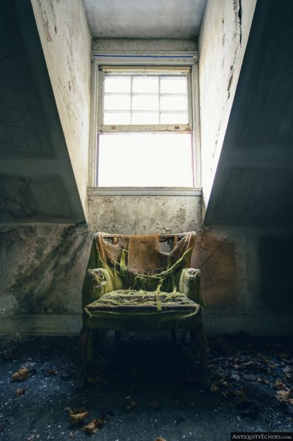 Damaged green chair placed below a window