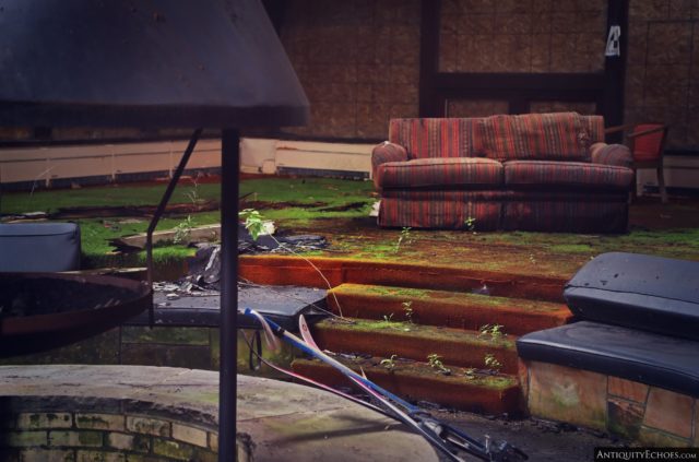 A red couch placed near some low-lying steps near an indoor fire pit