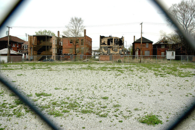View of vacant and burned buildings through a chainlink fence