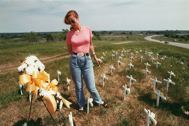 Woman standing among small white crosses