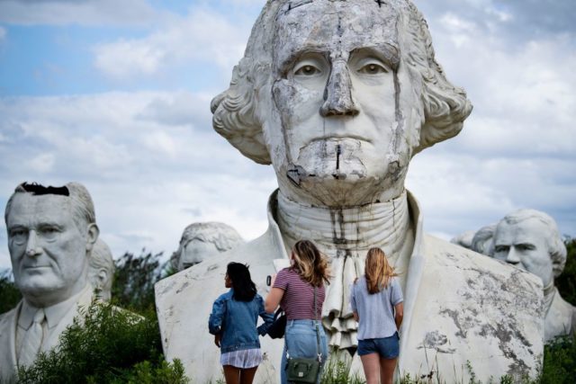 Three women standing in front of the bust of George Washington