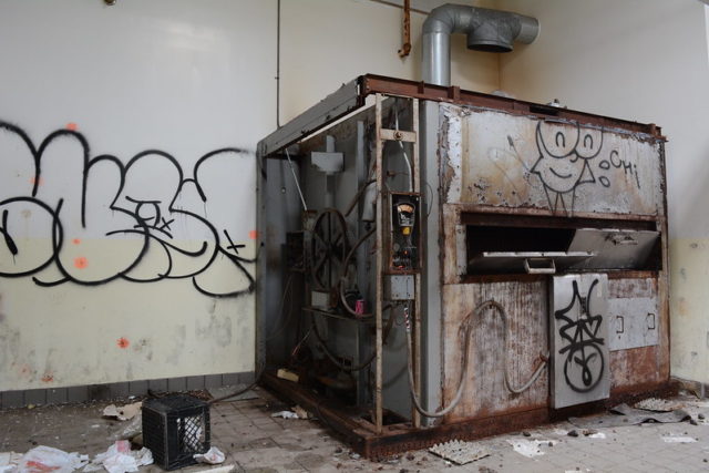 Graffiti-covered machine in the corner of a room