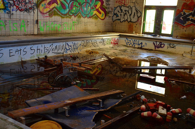 An abandoned swimming pool, graffiti on the walls, filled with garbage.