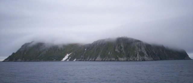 King Island, Alaska. The large boulders on the top of the island are barely visible through the fog. Author: Dave Cohoe CC BY 3.0