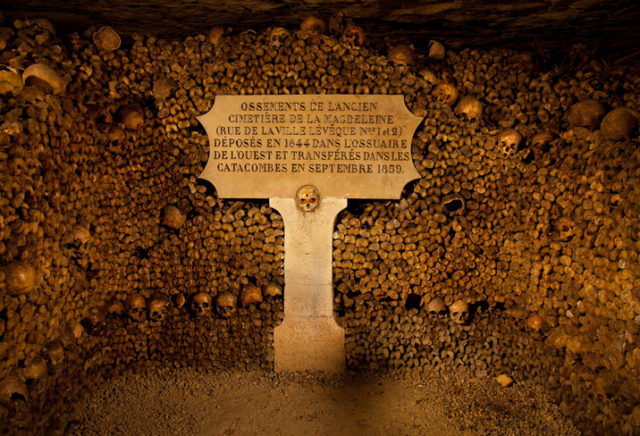 Piles of bones and skulls are arranged into a stack in the Paris’ Catacombs.