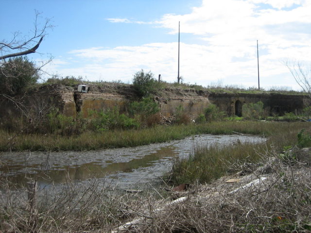 Ruins of Fort Macomb, Louisiana, and a portion of the remaining moat. Note appliance (refrigerator?) atop a wall, deposited there by Hurricane Katrina. Author: Infrogmation CC BY 2.5