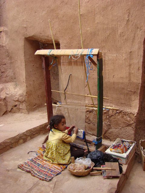 Little girl working on a loom in Aït Benhaddou, May 2008. Author: Zouavman Le Zouave CC BY-SA 3.0 