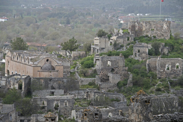 Stone buildings and a church on a hilltop.