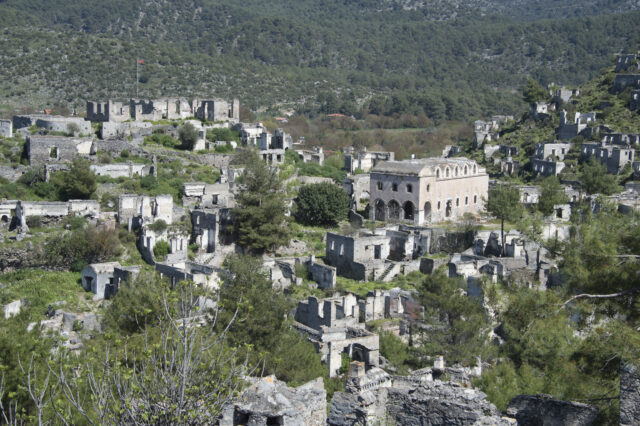 Stone buildings and a church on a hilltop.