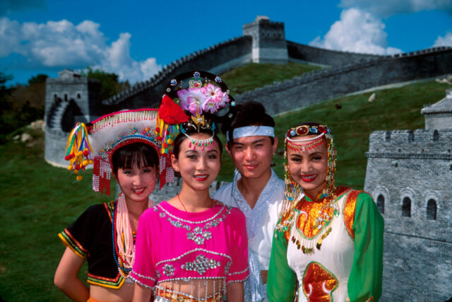 Four performers standing together in front of a backdrop of the Great Wall of China