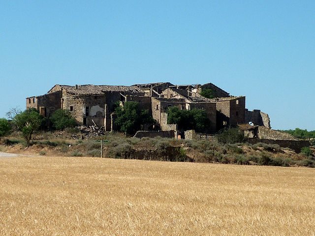 The ruins of Conill are overgrown with vegetation. Author: Isidre blanc – CC BY-SA 3.0