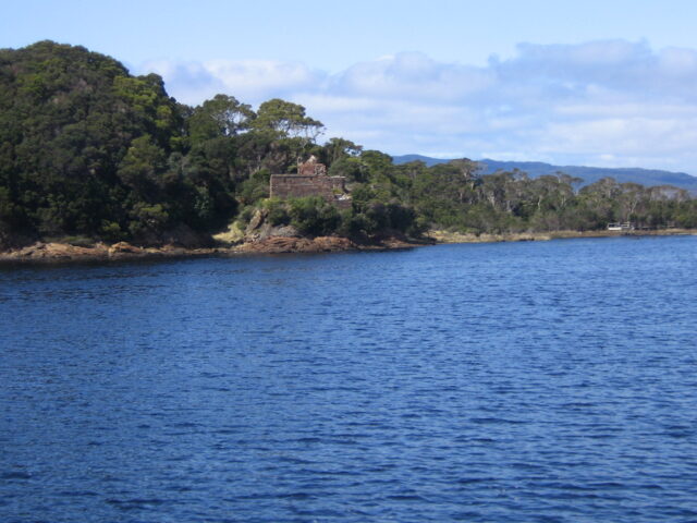 Photo of an island surrounded by water, a stone structure visible on its bank.