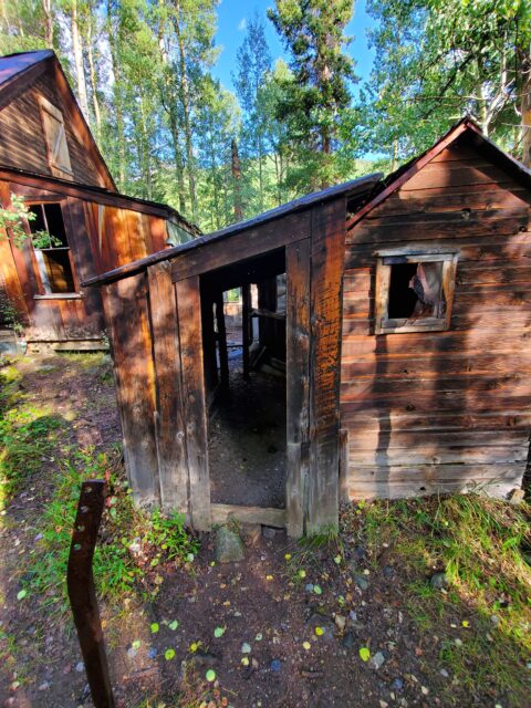 A close-up of two abandoned wooden shacks.