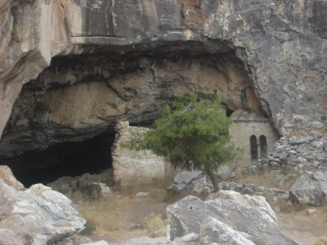 The entrance to the cave with the church to the right. Author: NikosFF CC BY-SA 4.0