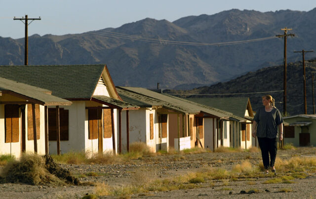 Woman walking past a row of boarded-up houses