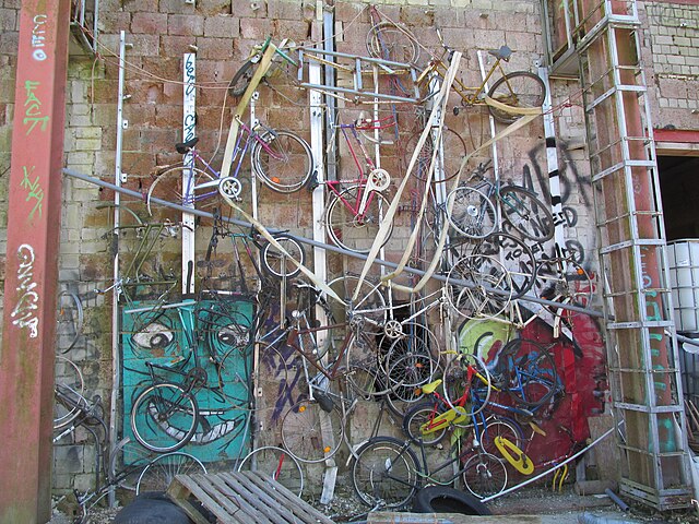 Bicycles stacked along a graffiti-covered wall