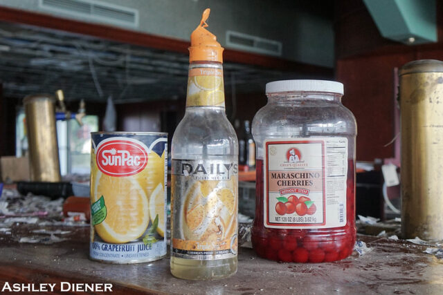 Can of grapefruit, an empty bottle and a jar of cherries on a table