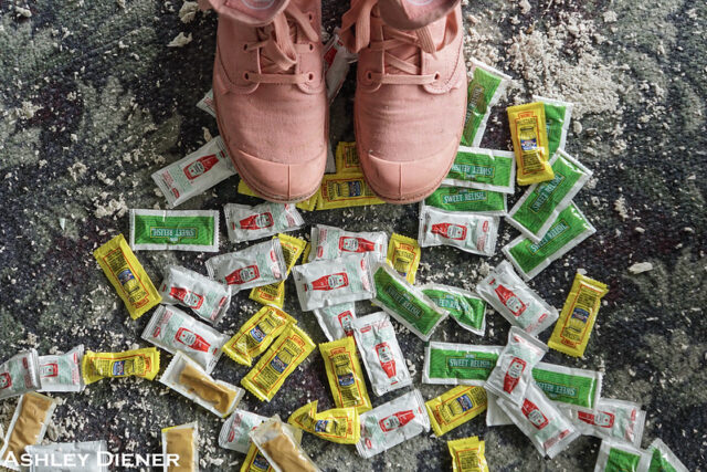 Pair of pink shoes over discarded ketchup packets