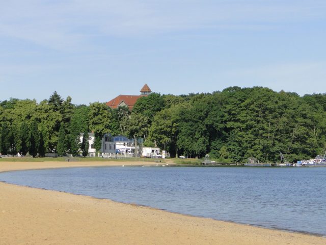 Beach and abandoned hotel in the background. By Niteshift (talk) – CC BY-SA 3.0