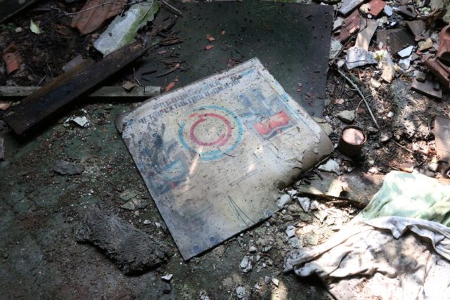 Paper with images on it on the ground, surrounded by debris