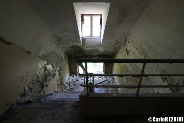 Overhead view of a darkened staircase lit by two small windows