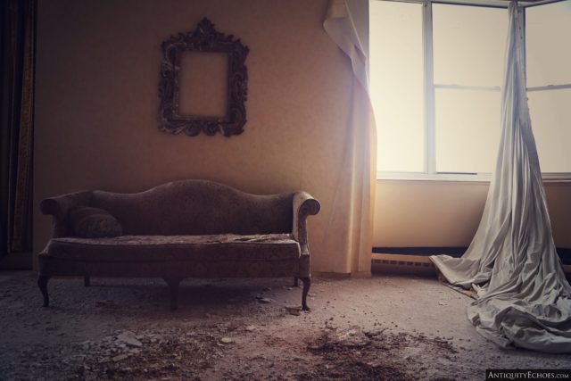 Old-style couch and empty picture frame placed to the left of a sunlit window