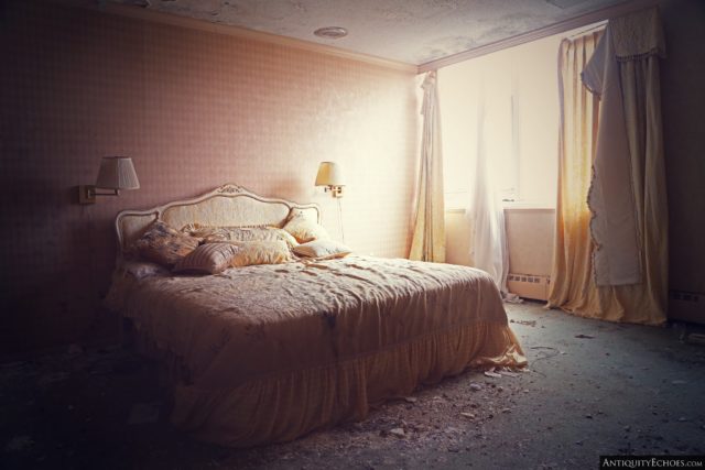 Large bed with lamps on either side in a sunlit hotel room within the Nevele Grand Resort