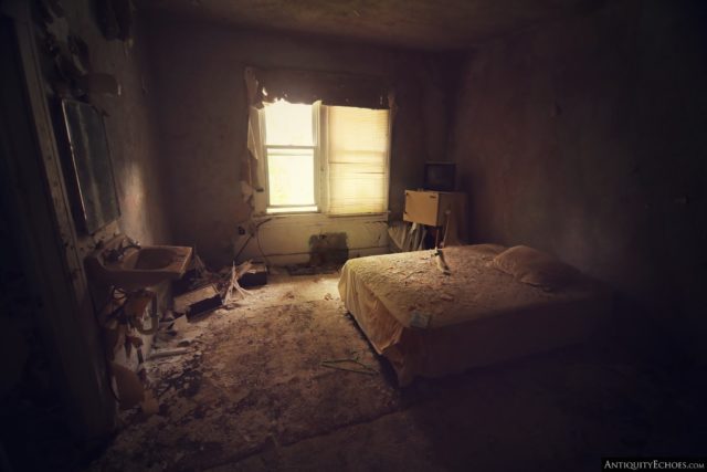 A dark hotel room in the Nevele Grand Resort, with a bed and bathroom sink at the center