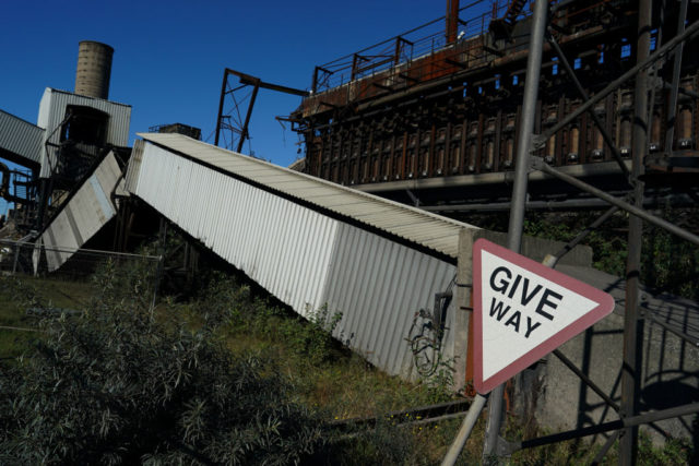 "Give Way" sign beside a metal shute that's been cut in half