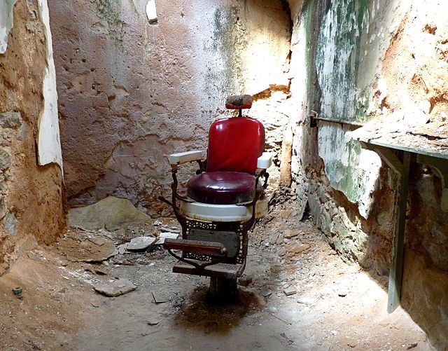 Red barber's chair in the middle of a decrepit room