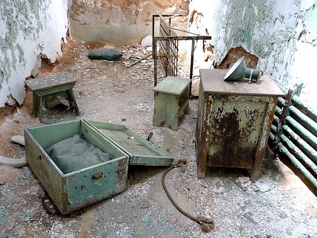 Various pieces of bedroom furniture in a derelict room