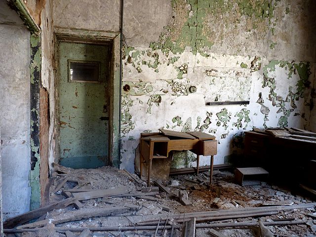 Empty room with a desk in the corner and debris on the ground