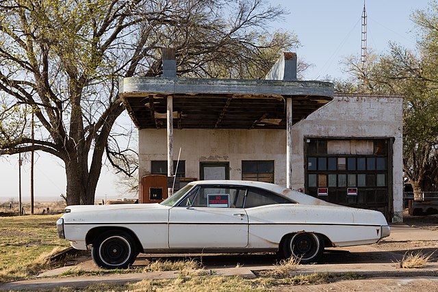 Vintage white car parked in front of a Glenrio gas station