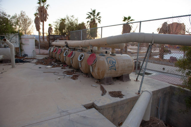 Row of rusty water tanks covered in graffiti