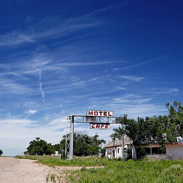 Faded motel and cafe sign along an empty road