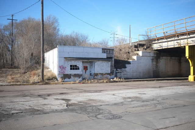 Small white building abandoned along an underpass