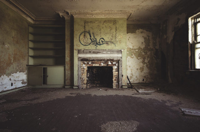 Dilapidated fireplace with graffiti overtop