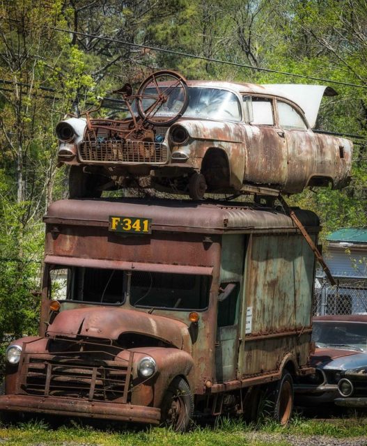 Rusty bicycle and car atop a rusty delivery truck