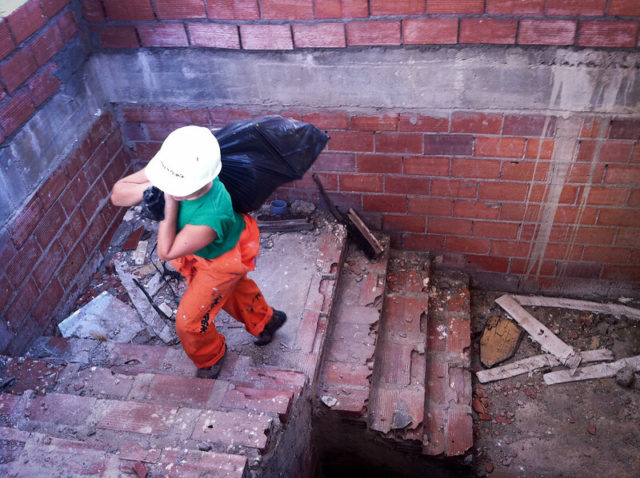 Person carrying a garbage bag up a brick staircase