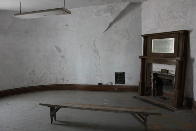 Wooden bench in an empty room with a fireplace