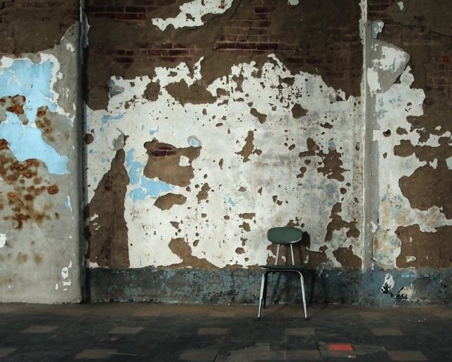 Blue chair in front of a wall of peeling paint