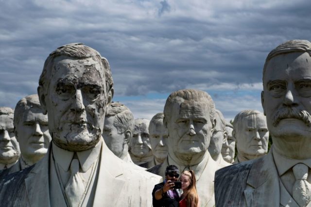 Couple taking a picture in front of the busts from Presidents Park