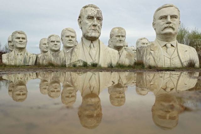 Busts from Presidents Park sitting by muddy water