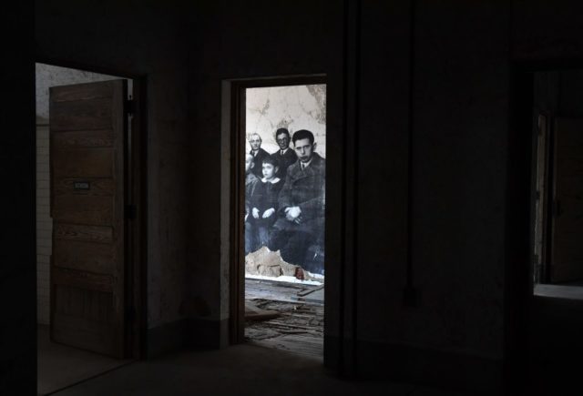 Darkened doorway leading to a room with photographs of immigrants glued to the wall