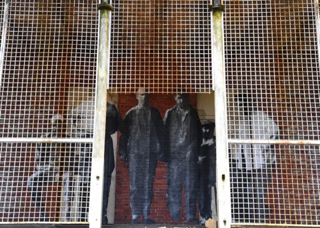 Photographs of immigrants behind a caged doorway at the Ellis Island Immigrant Hospital