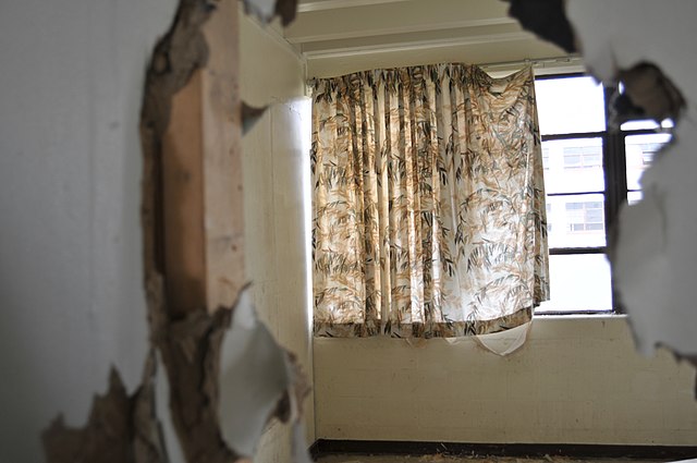 View of a curtain-covered window through a hole in the wall